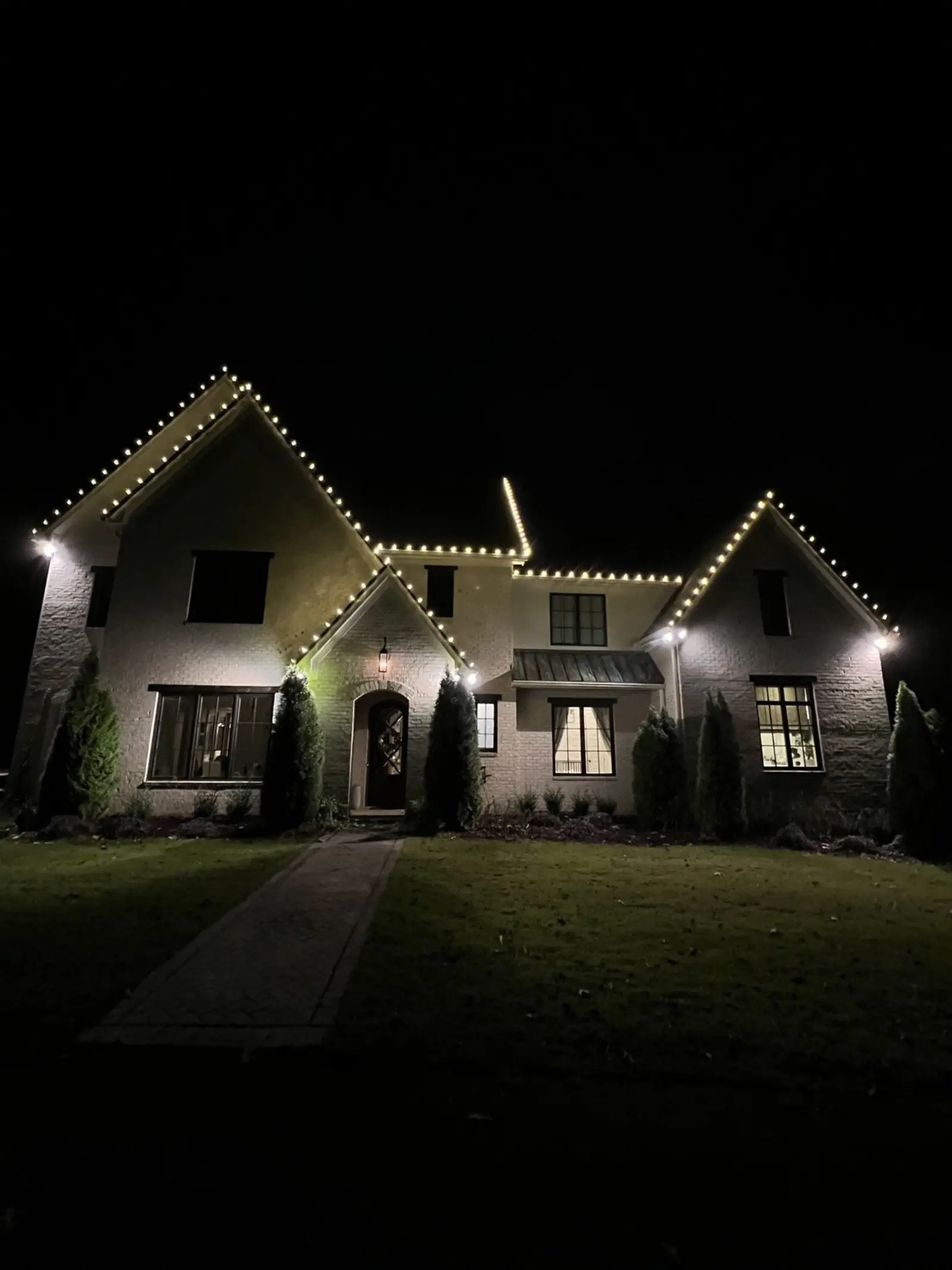 Two-story home at night with Christmas lights outlining every gable
