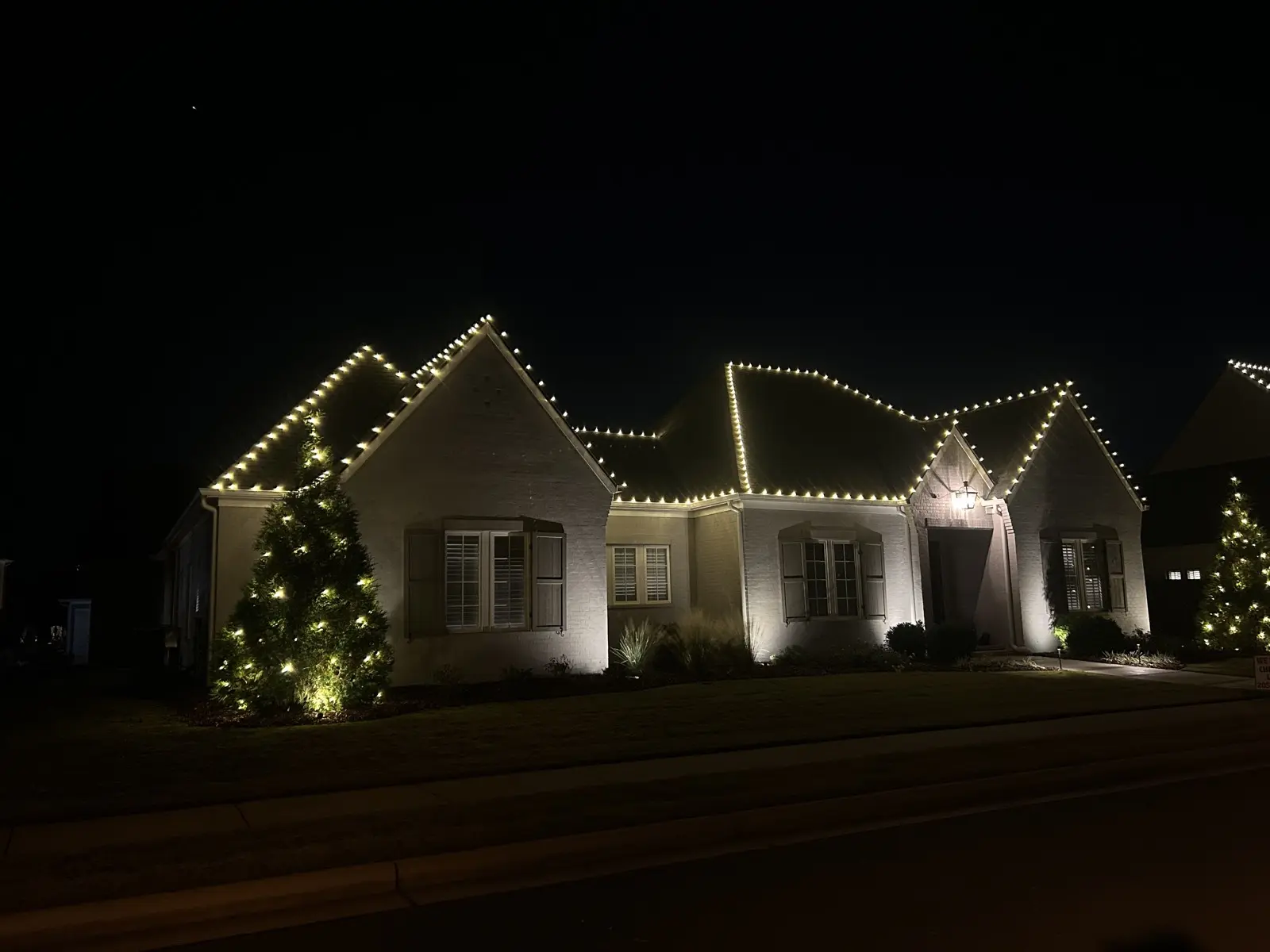 Home with Christmas roofline lighting and a wrapped outdoor tree